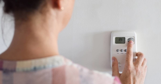 Woman adjusting thermostat settings