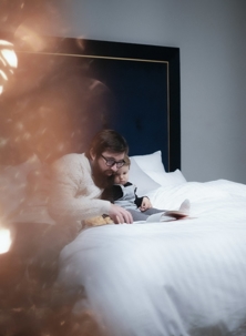 man and child reading in bed